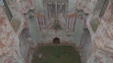 Siste açık pencereleri olan terk edilmiş eski tapınağın insansız hava aracı görüntüsü. Kamera antik tapınağı içeriden söker ve sonbahar ormanını sökerek ske tırmanır. 4K video.