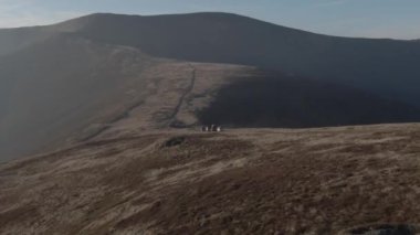 Gün batımında dağlarda uçan bir grup arabanın görüntüsü. Sisin içindeki dağların inanılmaz manzarası. 4K video.