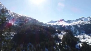 Derin karla kaplı dağ zirveleri manzarası. Kış ormanı üzerinde uçuyor. Destansı karlı dağlar. 4K video.