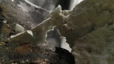 Şelalenin ortasındaki videoyu kapat ve yukarıdan akan suyu ve karla kaplı bir bölgeyi. 4K video.