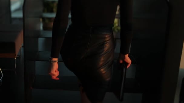Vista trasera de una señora jefe en una falda de cuero negro sube las escaleras en el centro de la oficina con una carpeta en la mano — Vídeos de Stock
