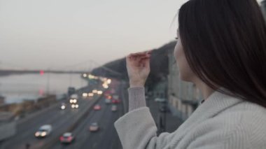 Balkonda şehir manzarası seyreden bir kadın. Balkonda gün batımının keyfini çıkaran bir kadın. Lüks hayat konsepti. Başarılı bir iş kadını.