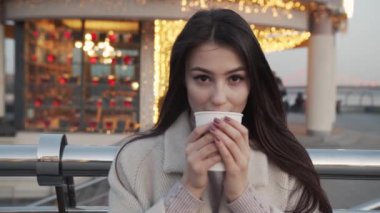 Yaşam tarzı, kadınlar ve duygular. Şehir parkında dikilen, neşeli, gülümseyen, baharın tadını çıkaran, en sevdiği kafeden kahve içen mutlu kızın açık hava portresi.