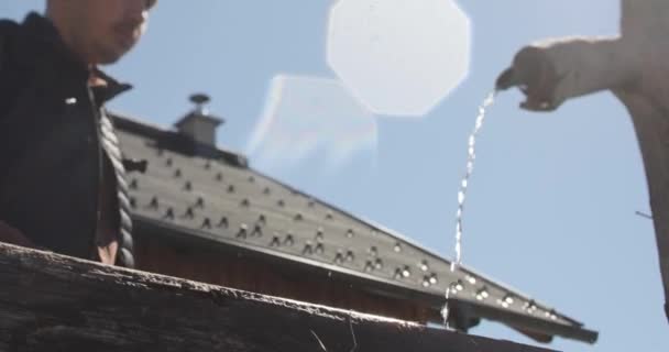 Verlichte beelden van een dorstige man die water drinkt uit een kraan met zijn handen op een hete zonnige dag. — Stockvideo