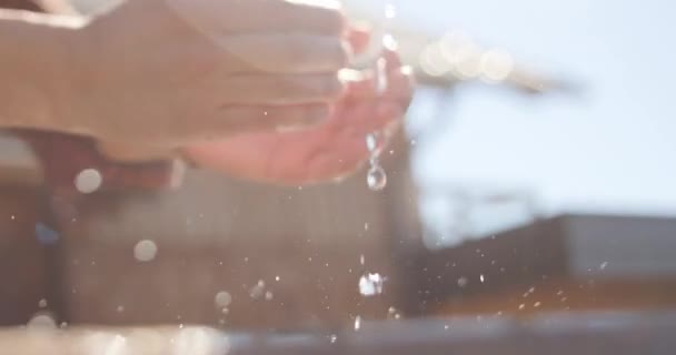 Slow motion, close-up shot of pure freshwater falling on a mans hands with some water splashing around — Stock Video