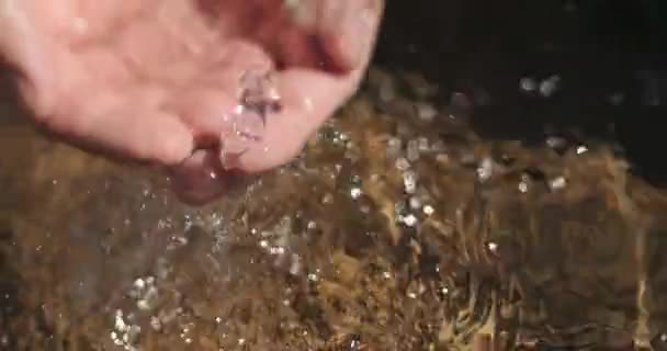 Primo piano colpo di acqua cristallina pulita che scorre nelle mani di un uomo con un po 'di esso schizzi giù nella piscina d'acqua — Video Stock