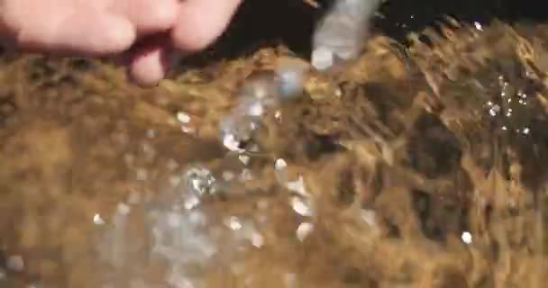 Imagens de close-up super de água cristalina caindo em uma piscina no fundo e mãos vindo para buscar alguns — Vídeo de Stock
