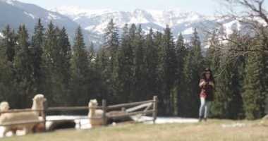 Şapka ve güneş gözlüğü takan esmer bir kadının görüntüsü bir lama sürüsünün kaleminin yanından geçti..