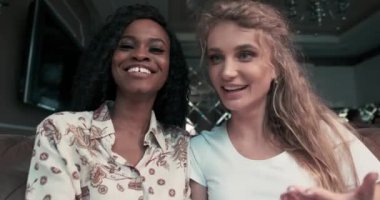 İki mutlu arkadaş Afro-Amerikan ve Kafkasyalı laptopta görüntülü sohbeti bitiriyorlar, gülüyorlar, el sallıyorlar ve öpüşüyorlar..