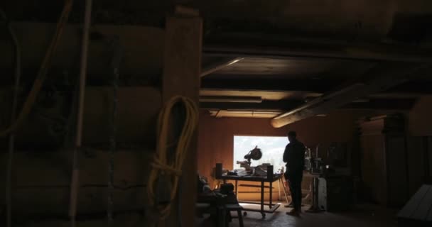 Filmagem em câmera lenta da slhouette de um carpinteiro fazendo medições enquanto trabalhava em uma oficina. — Vídeo de Stock