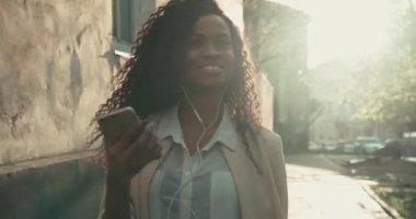 Güzel bir Afro-Amerikalı kadının müzik dinleyip akıllı telefonuyla selfie çektiği yakın plan görüntüsü. Dışarıda eğlenmek için.