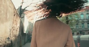 Neşeli, Afro-Amerikan bir bayanın yakından çekilmiş görüntüsü. Güneşli bir günde saçlarını sallayarak sokakta heyecanlı bir şekilde yürüyor..