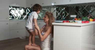Bir annenin, o mutfaktayken küçük oğlunu bacağında zıplatırken ki görüntüsü. Anne ve oğul kaynaşma zamanı..