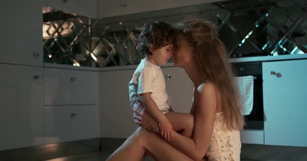 Nahaufnahme von einem glücklichen Kleinkind mit Mutter Reibnasen auf dem Küchenboden sitzend. Mutterzärtlichkeit — Stockvideo