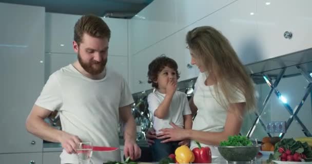 Feliz familia mamá, papá e hijo cocinando verduras frescas juntos. Tiempo de vinculación familiar. — Vídeos de Stock