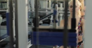 Yoğun kardiyo egzersizi sırasında, odaklanmış, güzel, sarışın bir fitness kadınının düşük tutumlu kablo egzersizinin yavaş çekim görüntüleri..