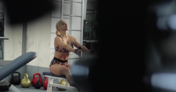 Plein plan, vidéo au ralenti d'une belle femme de fitness blonde concentrée effectuant un exercice de câble à large adhérence à faible rangée pendant la routine d'entraînement cardio intense. — Video