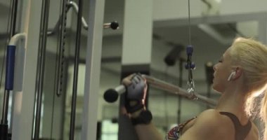 Yakından, yavaş çekimde, spor salonundaki yoğun kardiyo egzersizi sırasında, at kuyruklu genç sarışın bir bayanın bariyeri indirirkenki görüntüsü..