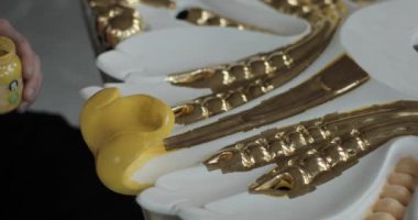 Sarı boyayla dikkatlice boyanmış bir ev süslemesinin yavaş çekim görüntüleri..