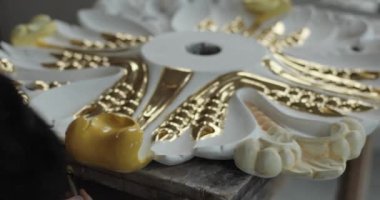 Bir ev süslemesinin altın boyayla dikkatlice boyandığı yavaş çekim görüntüleri.