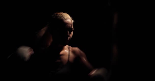Close-up side view beelden van een vastberaden blonde bokser die agressief toeslaat op een bokszak tijdens de training. — Stockvideo