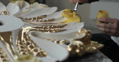 Evin süslemelerini sarı boyayla dikkatlice hazırlayan bir elin yakın çekim görüntüleri..