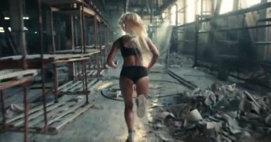 Sabahın erken saatlerinde fabrikada koşan kaslı sarışın bir sporcunun yavaş çekim videosu.