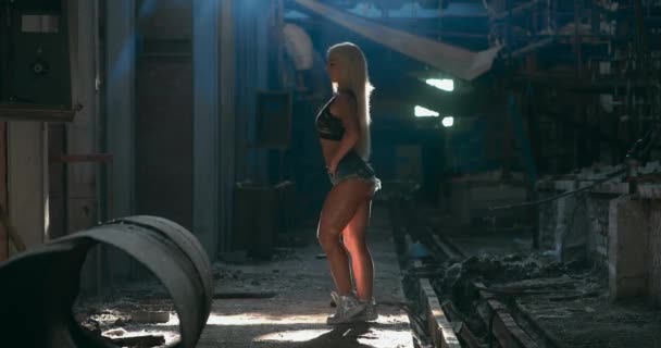 Full-shot de la joven modelo rubia de fitness haciendo ejercicio de pantorrilla suave en una fábrica. — Vídeos de Stock