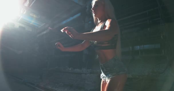 Vue rapprochée d'un modèle de fitness caucasien attrayant faisant l'exercice de swing des jambes et d'étirement du bras vers l'avant en arrière-plan d'usine — Video
