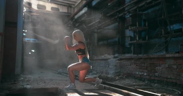 Pełne ujęcie atrakcyjnej kaukaskiej modelki fitness wykonującej uderzenie do przodu w fabrycznym tle — Wideo stockowe