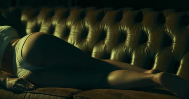 Cámara lenta de vídeo de una joven encantadora mujer seductora tumbada en un sofá en la sala de estar. — Vídeo de stock