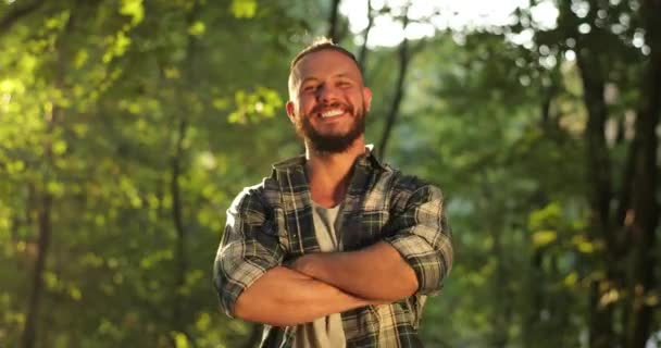 Portret młodego uśmiechniętego mężczyzny stojącego w lesie. Ludzie w Naturze. One 30s Człowiek osoba patrząc w aparat fotograficzny na tle lato krajobraz zbliżenie — Wideo stockowe
