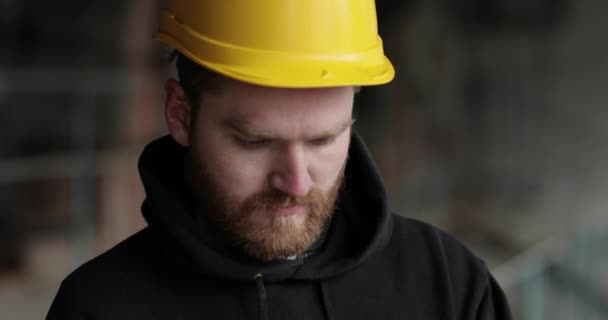 Ritratto ravvicinato di un uomo con un cappello giallo e la barba. il padrone guarda davanti e sorride — Video Stock