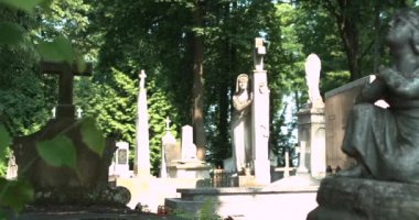 Güneş, eski mezarlıktaki taş heykellerin üzerinde batıyor. Dua eden bir meleğin taş heykeli