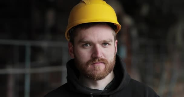 Portrait en gros plan d'un homme dans un casque et avec une barbe rouge regarde droit dans la caméra et rit. — Video