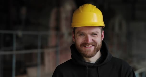 黄色いヘルメットの幸せそうな男が真っ直ぐに笑ってる。赤い髭を生やした男が. — ストック動画