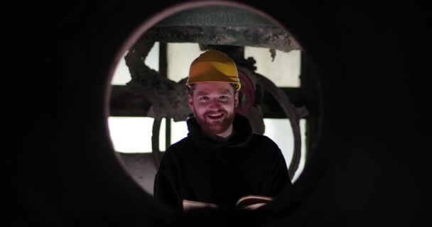 Ritratto di un uomo barbuto in casco in cerchio. uomo in casco giallo tiene la carta in mano e sorride — Video Stock