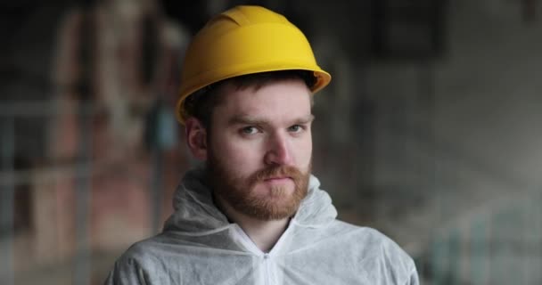 Joven barbudo con abrigo blanco y casco amarillo. Ingeniero de fábrica. maestro en el ataúd — Vídeos de Stock