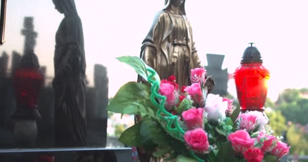 Golden sculpture of Mary in the cemetery. Grave candles. Artificial flowers — Stock Video
