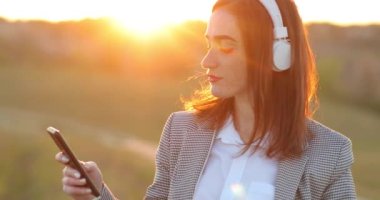 Genç ve mutlu bir kadın, arka planda izole edilmiş kulaklıklardan müzik dinlemekten zevk alıyor. Çilli kız suratı. Beyaz kulaklıklı kızıl saçlı güzel kız. Kızıl saçlı kız dinliyor.