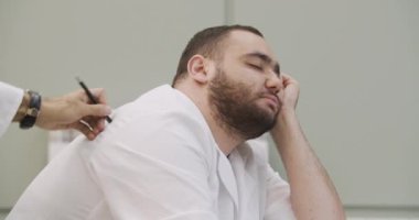 Üniversite konferansı sırasında uyuyan genç bir adam. Sıkılmış ve yorgun öğrenci uyuyor. Sakallı erkek öğrenci koluna yaslanmış bir derste uyuyor..