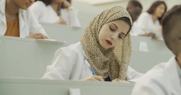 Muslim female student. A Muslim young woman in a hijab sits at a lecture at the university. Arabic Student. — Stock Video