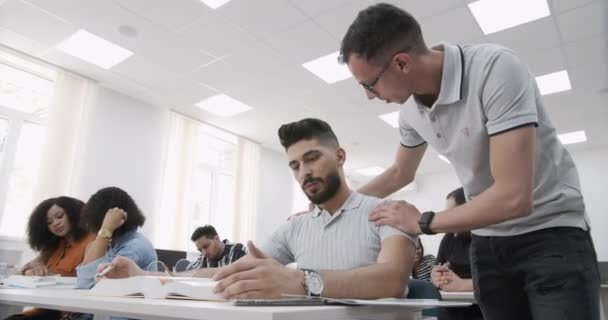 Multietnisk grupp av studenter som arbetar med uppgifter tillsammans. Grupp av mångfald högskolestudenter lärande på campus, indiska, svarta och indonesiska människor. — Stockvideo