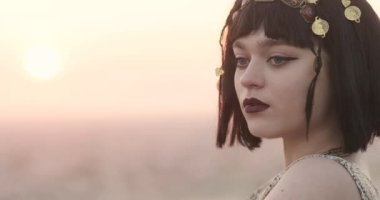 Kısa siyah saçlı çekici bir kızın yakın plan portresi. Altın mücevherli kız. Genç kadının net ve belirgin bir yüz hatları var. Gizemli ve delici bakışlar