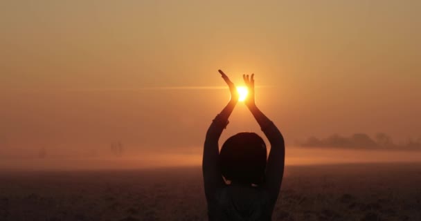 Flicka som dansar vid solnedgången. Händerna leker med solen som en boll. vacker solnedgång. flicka rör sig sexuellt på fältet vid solnedgången. smal damsiluett vid solnedgången. — Stockvideo