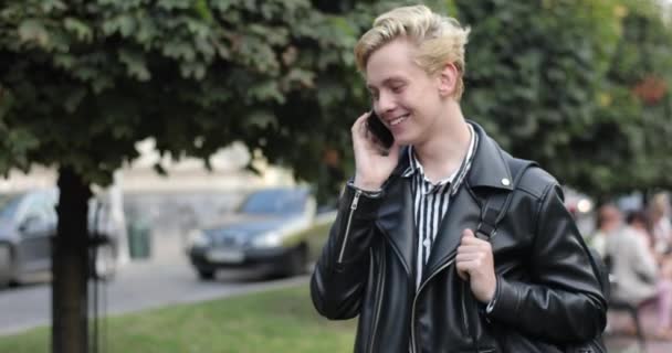 Симпатичная блондинка идет по улице и разговаривает по телефону. — стоковое видео
