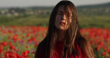 Haşhaş tarlasının ortasında kırmızı elbiseli, doğa güzeli bir kadın. Onun mükemmel kumral, uzun saçları rüzgarda uçarken güneş ışınları onun üzerinde parlıyor.