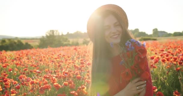 Jolie fille dans un chapeau dans un champ de fleurs. Jeune belle femme sourit et s'amuse dans le domaine. Vue de portrait. Gros plan. 4K. — Video