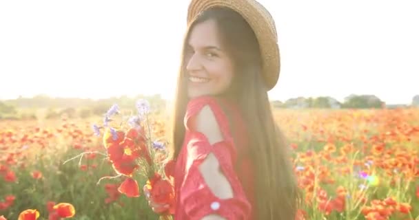 Portrait de jolie fille dans un champ rouge de fleurs. Jeune belle femme avec un sourire charmant a des fleurs à la main dans le domaine. Vue de portrait. Gros plan. 4K. — Video