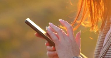 Telefon ve kızıl kadın saçlarıyla ellerini kapat. Güzel manikür. doğa arkaplanı